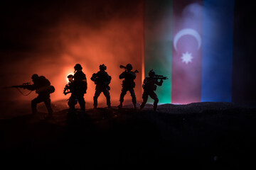 Azeri army concept. Silhouette of armed soldiers against Azerbaijani flag. Creative artwork decoration. Military silhouettes fighting scene dark toned foggy background.