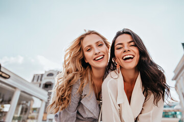 Inspired laughing ladies posing together on sky background. Outdoor photo of interested caucasian...