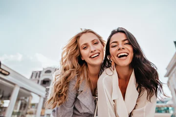 Fotobehang Inspired laughing ladies posing together on sky background. Outdoor photo of interested caucasian sisters enjoying good day. © Look!