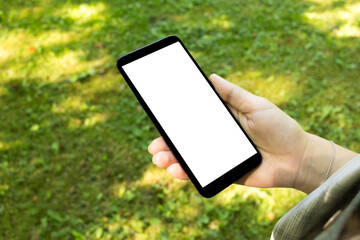 Top view mock up image of woman holding mobile phone with blank white desktop screen on grass background
