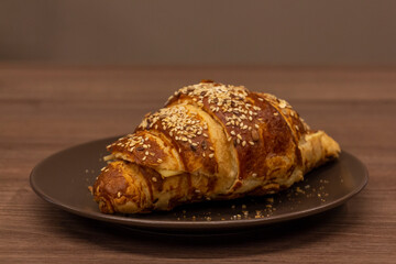 Close up view of tasty croissant sprinkled with sesame and made from puff pastry. Selective focus. Fresh pastry theme.