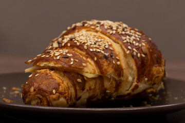 Close up view of tasty croissant sprinkled with sesame and made from puff pastry. Selective focus. Fresh pastry theme.