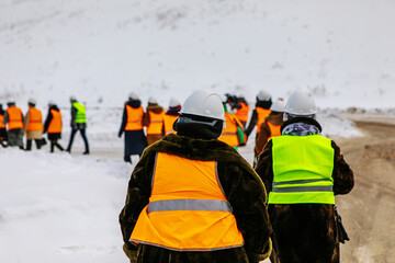 Many construction workers go to a construction site. Unrecognizable faces. Winter time