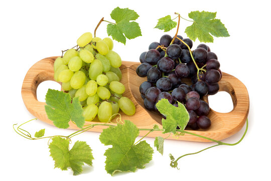 Bunches of grapes with leaves in the wooden tray isolated on white background