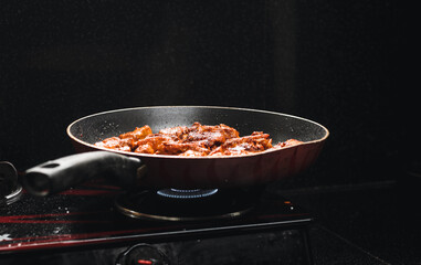 chicken frying in a hot pan on a stove