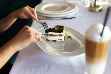 Young woman eating cake next to coffee