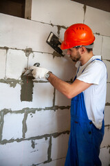 Mason aligning aerated autoclaved concrete block of constructed house wall