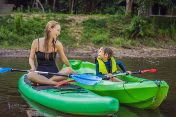 Happy young boy holding paddle in a kayak on the river, enjoying a lovely summer day