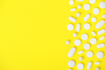 Bright yellow background with white medicine tablets	