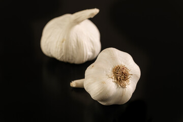 Zwei Knollen Knoblauch / Knoblauchzwiebeln auf schwarzem Hintergrund