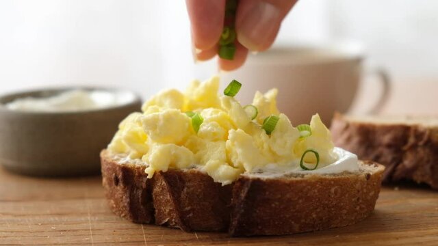Toast with scrambled egg and scallions. Slow motion garnish scrambled egg toast with chopped scallion
