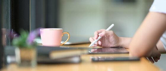 Closeup creative woman using digital tablet with stylus pen.