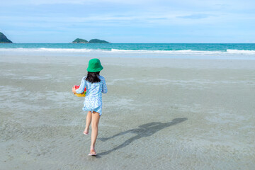 Rear view of child girl running on the beach in summer, let’s go to the beach.