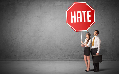 Young business person holding road sign with HATE inscription, new rules concept
