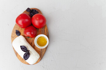 mozzarella cheese, tomatoes, olive oil and purple basil on a gray background. copy space. top view