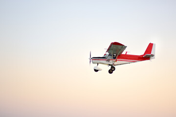 Small ultralight airplane with overhead wing and single propeller flying in sky. Such aircraft are used for recreational, sport and flight training. - obrazy, fototapety, plakaty