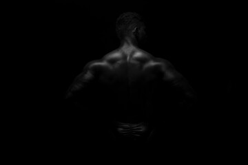 Fototapeta na wymiar Silhouette of young athlete bodybuilder man on black