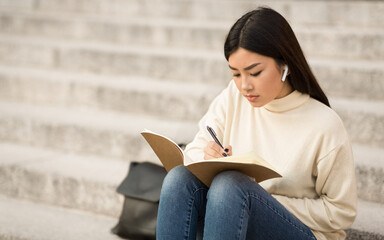 Girl writing in diary, sitting on the steps