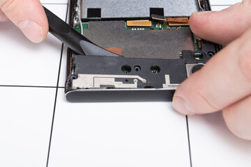 Mobile phone repair. Wizard detaches smartphone parts