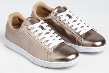 Gold shiny sneakers isolated on white background. 