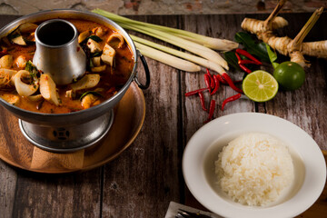 A delicious seafood soup of Thai people in a hot pot on a black background. Seafood Tom Yum with Coconut Milk