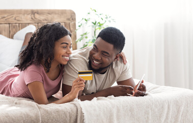 African happy couple buying online, using smartphone and credit card