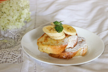 Fried toast with bananas in bed and a glass of wine