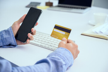 A man using a smart phone and holding a panoramic banner of a credit card Young businessmen or entrepreneurs who work at the office Online shopping