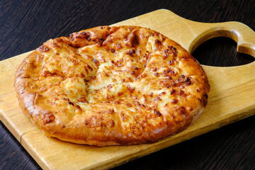 Georgian khachapuri Mergoli on a cutting Board. National cheese tortilla. Toasted delicious crust. The concept of healthy eating.
