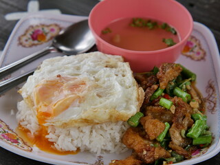 crispy pork belly basil stir fried with fried egg and soup on a wooden table,thai food.