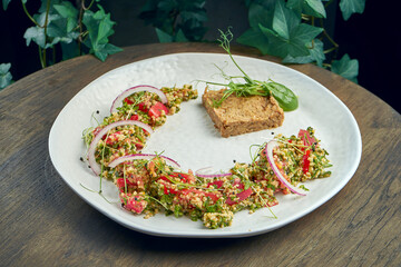 Oriental Tabbouleh salad with quinoa and onions, garnished with stewed duck fillet. Selective focus