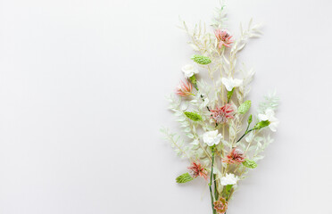 Flower composition made of dried light-green leaves of ruscus and white flowers on pastel grey background. Nature concept, copy space, flat lay.