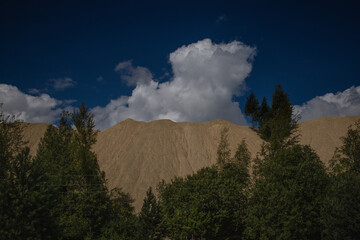 clouds float over a mountain of waste lime sludge
