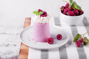 Raspberry mousse topped with whipped cream and berries served on the ceramic plate