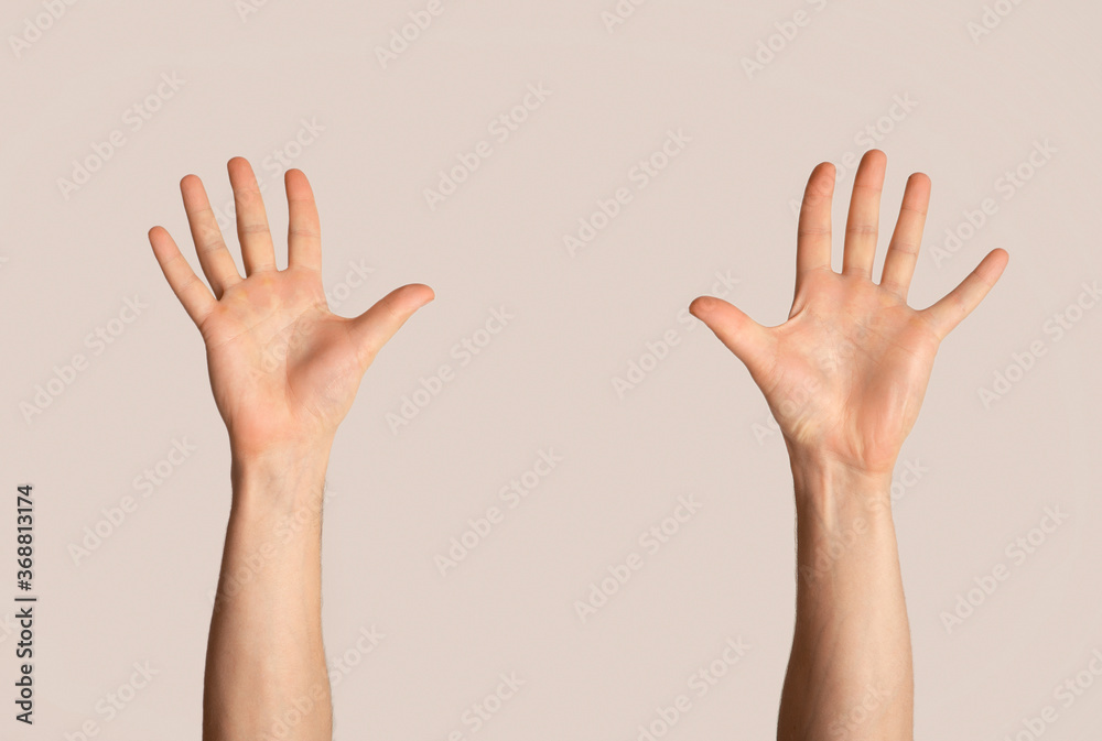 Wall mural millennial man raising both hands up on light background, closeup