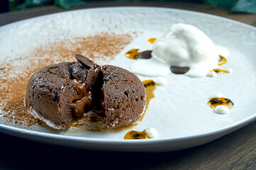 Dessert - chocolate fondant with white ice cream and chia in a white plate