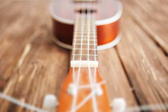 Photo depicts musical instrument ukulele guitar on a wooden