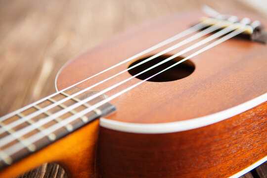 Photo depicts musical instrument ukulele guitar on a wooden