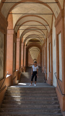 Asian woman in hat and sneakers standing in the middle of a stairway in a portico