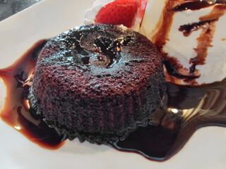 Warm chocolate fondant lava cake serving with strawberries on white plate. Valentines day dessert
