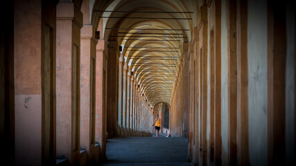 Woman in orange shirt and black shorts jogging throught the middle of a portico © David