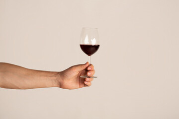 Male hand holding glass of red wine on light background, closeup with copy space