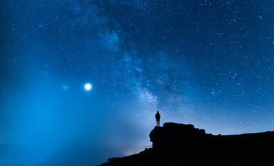 Person contemplating the vastness of the universe. Small silhouette of a man under the Milky Way...