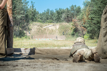 Soldier aims at a target on a military training ground lying down, selective focus.