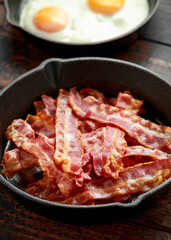 Fried crunchy Streaky Bacon pieces in a cast iron skillet