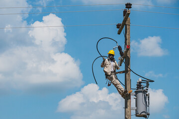 Lineman climb concrete pole are installing hotline-clamps to the ends of insulated electrical cables. To prepare for the installation of a single phase transformer into a high voltage distribution.