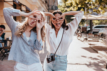 Appealing young ladies enjoying good weather. Outdoor portrait of gorgeous girls having fun together.