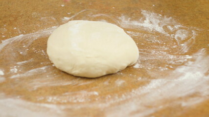 The woman or man on the table roll out the dough for cookies, pizza, pasta
