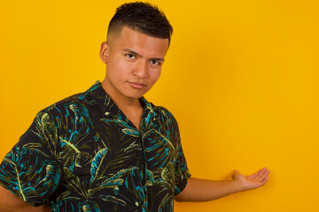 Portrait of handsome Young man with arm out in a welcoming gesture over gray background.