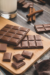 milk dark chocolate tiles on wood cutting board, wooden background